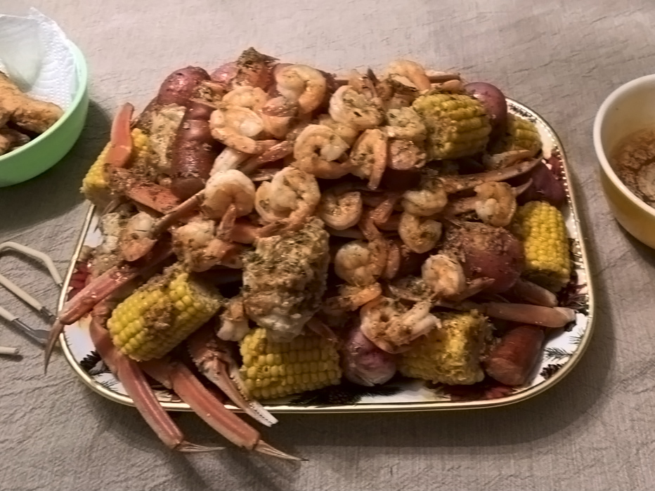 A delicious plate of food with succulent shrimp, golden corn, and savory potatoes. A mouthwatering feast!