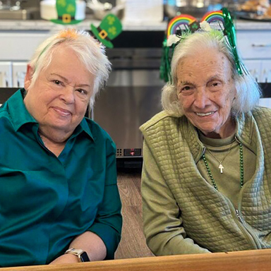 Two senior friends share a table and a relaxed moment in the bistro at Vitalia Mentor.