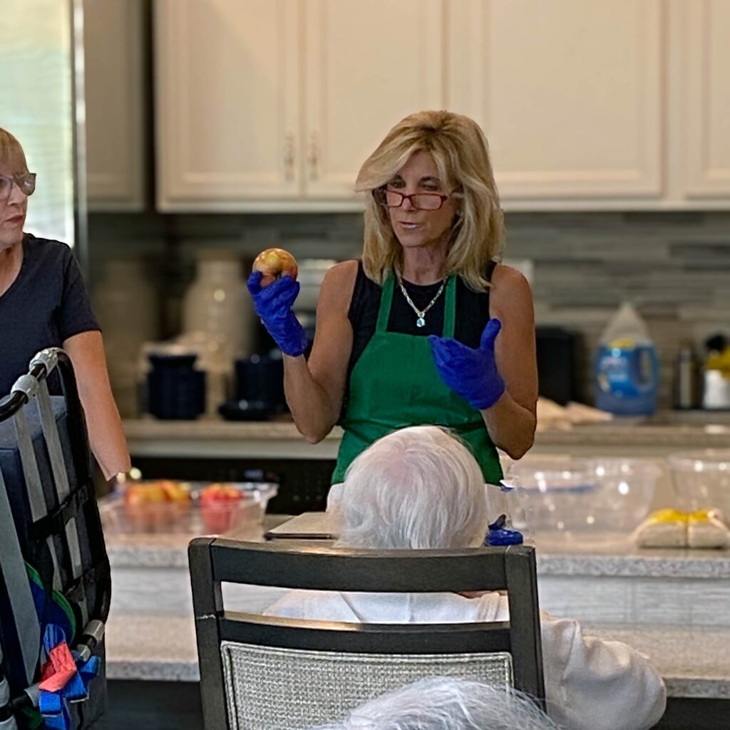 A woman in a green apron gives a kitchen demonstration at Vitalia Mentor.